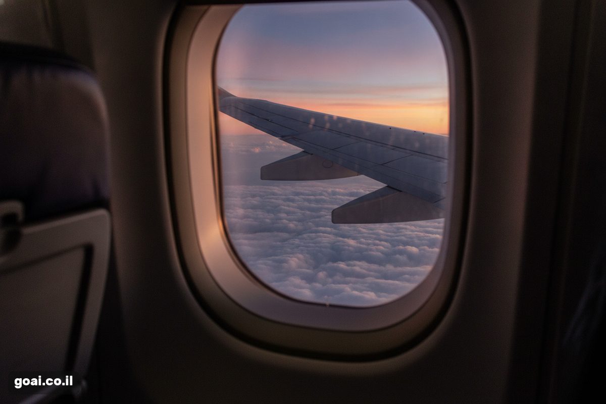 Flight Deals: כנף מטוס מחלון מעל עננים בשקיעה